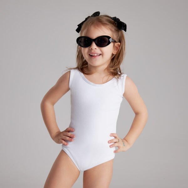 'Mini BIANCO' 5 Smiling young girl in a white swimsuit and black sunglasses poses confidently with hands on hips against a plain gray background.