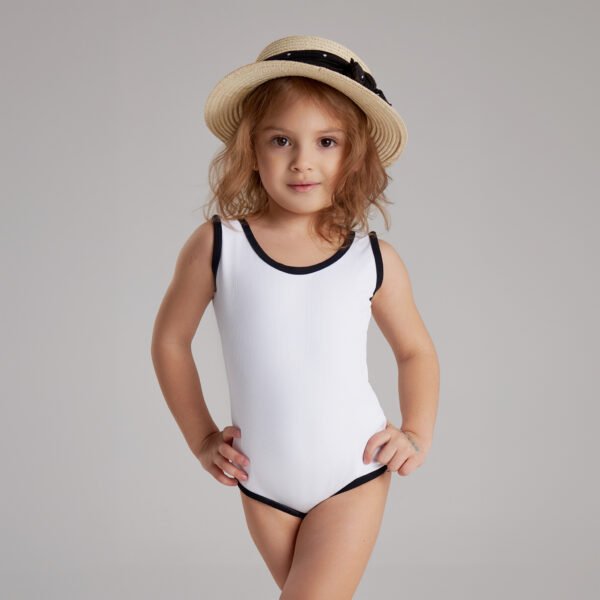 'Mini PANDA' 7 Young girl wearing a white one-piece swimsuit with black trim and a straw hat, posing confidently in studio setting.